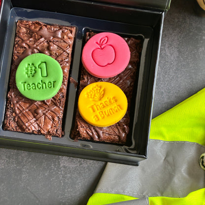 A closeup of two bars of fudgy chocolate brownies, decorated witrh edible messages perfect for gifting to educators and teachers alike!